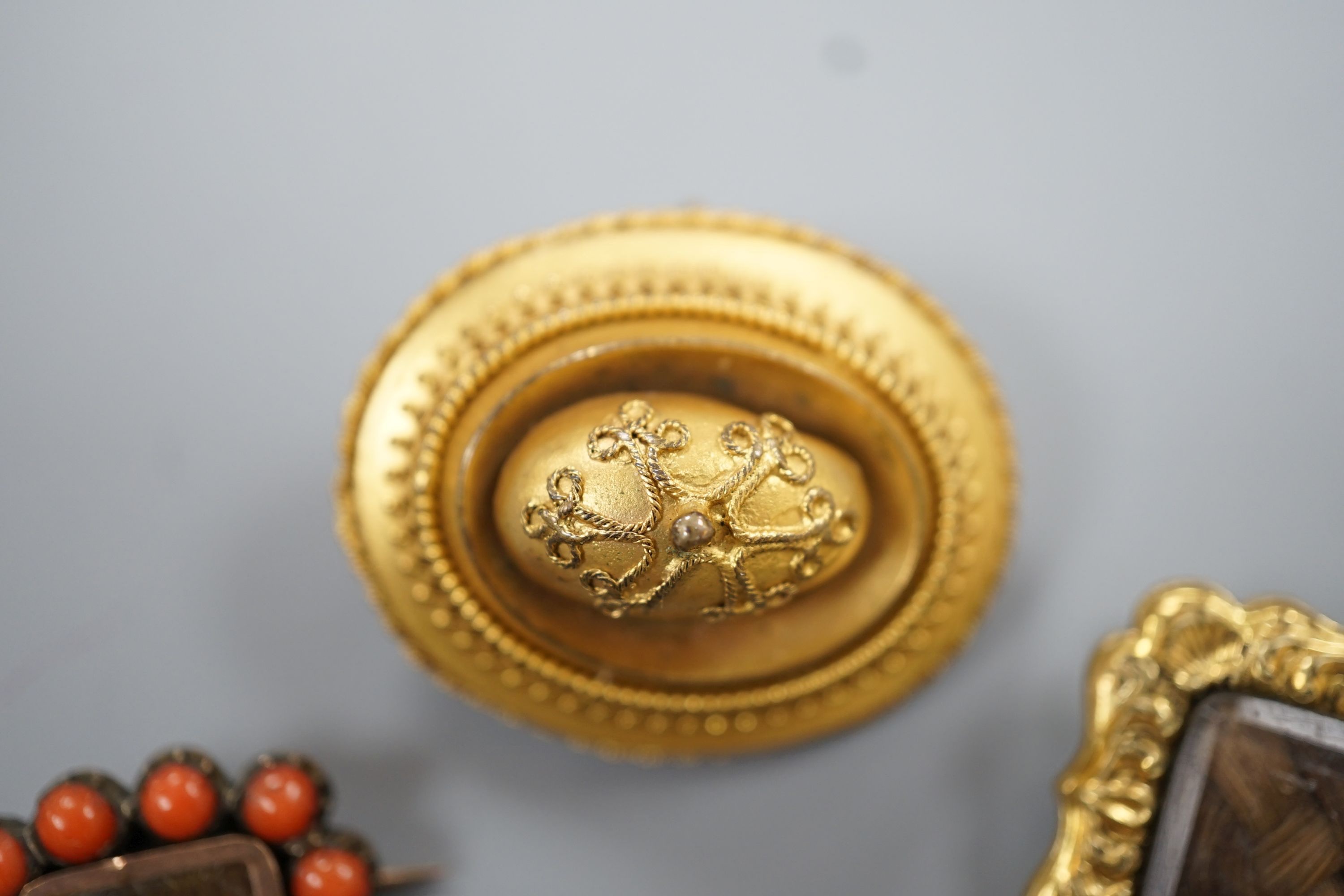 Two 19th century gilt metal and plaited hair set mourning brooches, two other mourning brooches and an oval pinchbeck brooch, largest 34mm.